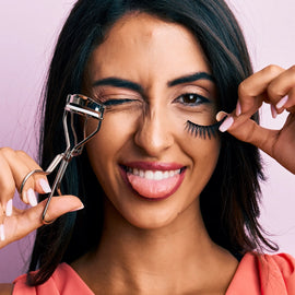 Spanish woman with natural lashes holding eyelash extensions and eyelash curler