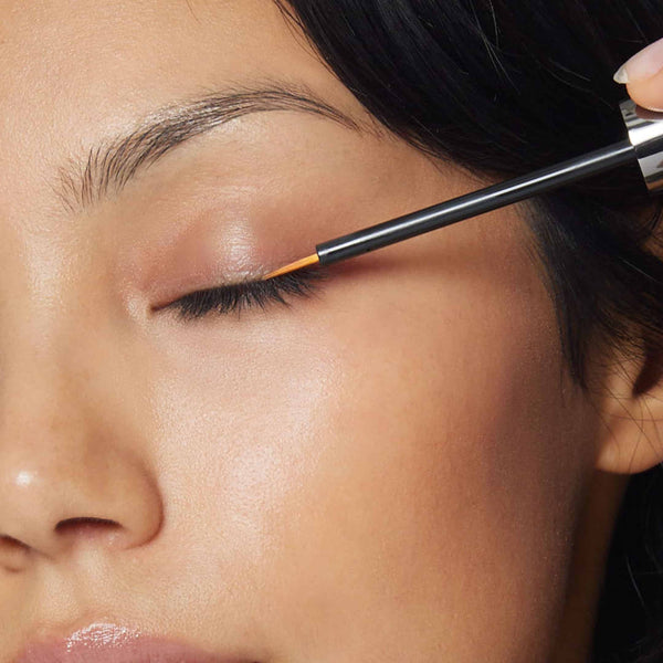 Image of Asian woman applies a thin layer of serum along the lash line.